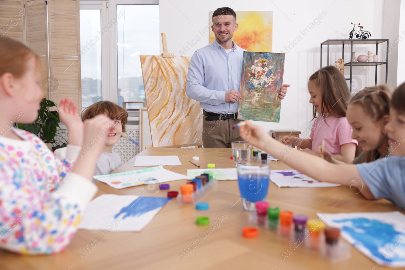 Kids with teacher at painting lesson indoors. Learning to draw Photo of Kids with teacher at painting lesson indoors. Learning to draw