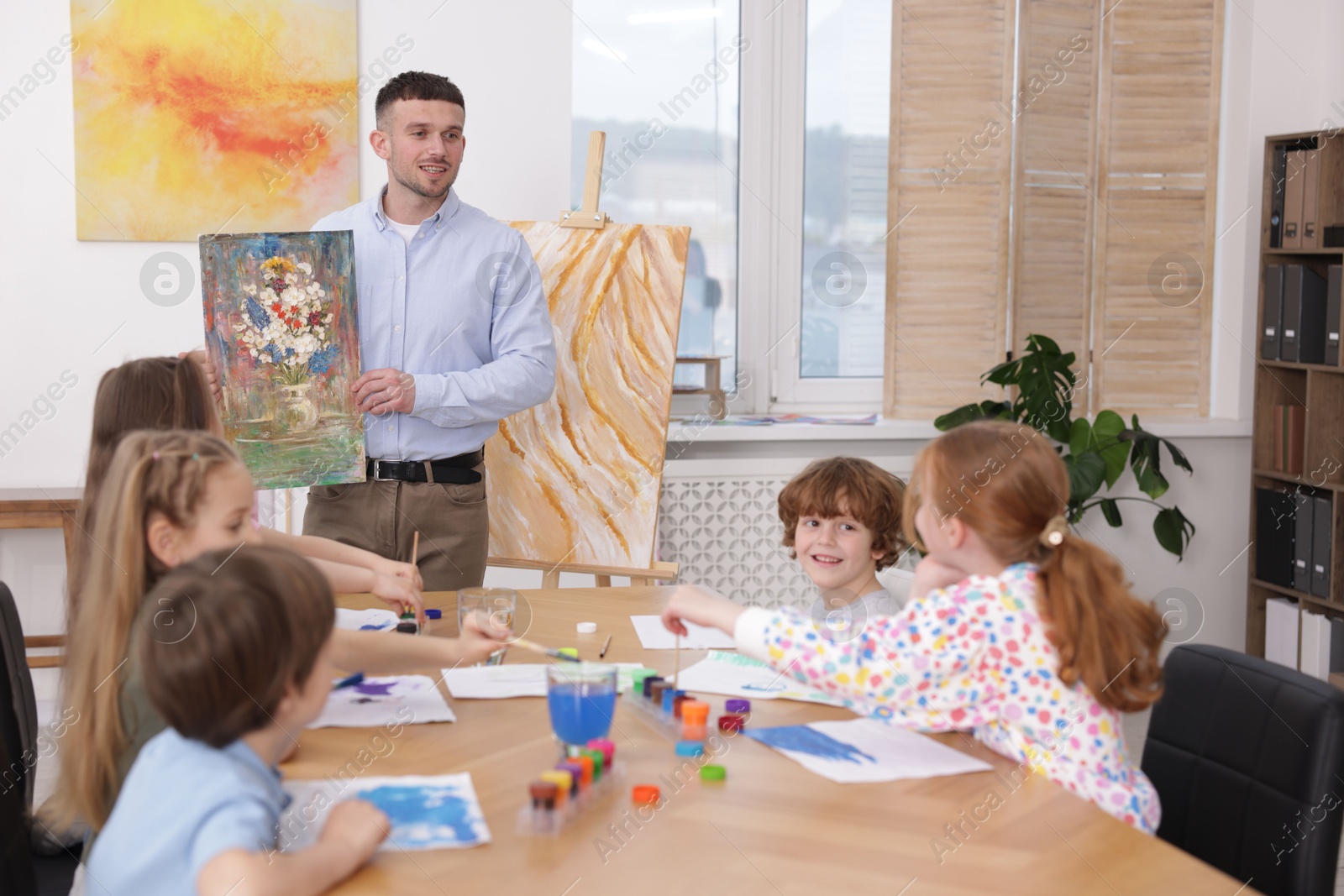 Kids with teacher at painting lesson indoors. Learning to draw Photo of Kids with teacher at painting lesson indoors. Learning to draw
