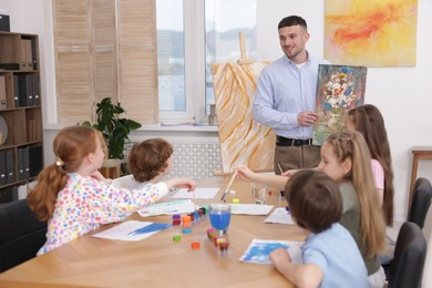 Photo of Kids with teacher at painting lesson indoors. Learning to draw