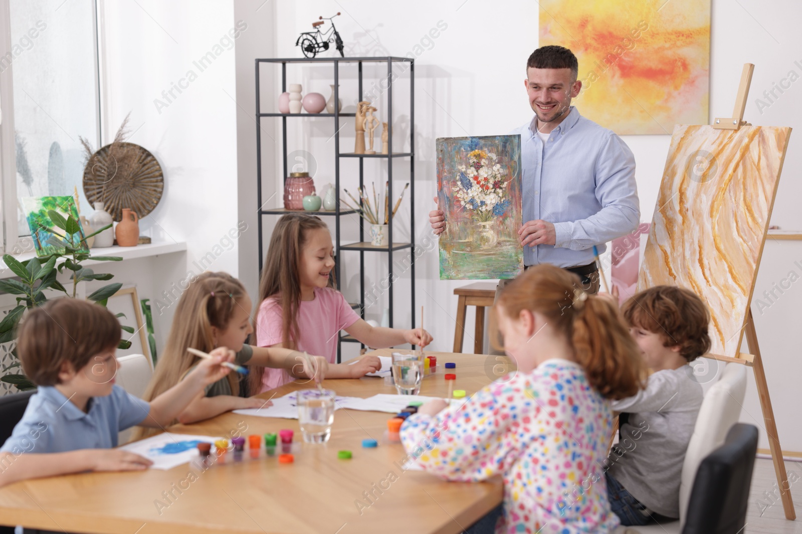 Kids with teacher at painting lesson indoors. Learning to draw Photo of Kids with teacher at painting lesson indoors. Learning to draw