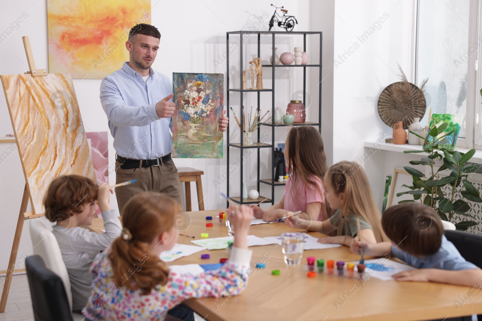 Kids with teacher at painting lesson indoors. Learning to draw Photo of Kids with teacher at painting lesson indoors. Learning to draw