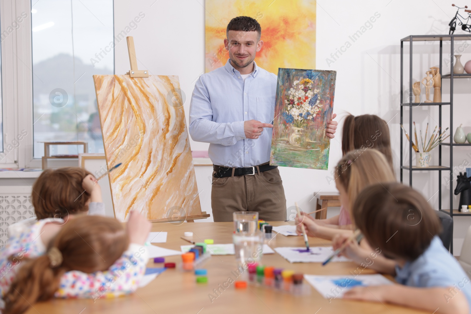 Kids with teacher at painting lesson indoors. Learning to draw Photo of Kids with teacher at painting lesson indoors. Learning to draw
