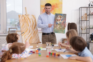 Photo of Kids with teacher at painting lesson indoors. Learning to draw