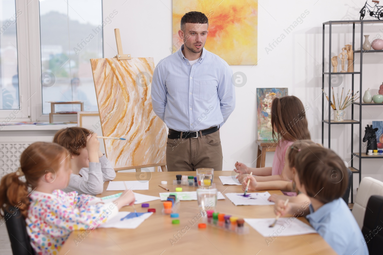 Man teaching kids to draw at painting lesson indoors Photo of Man teaching kids to draw at painting lesson indoors