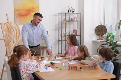 Photo of Man teaching kids to draw at painting lesson indoors