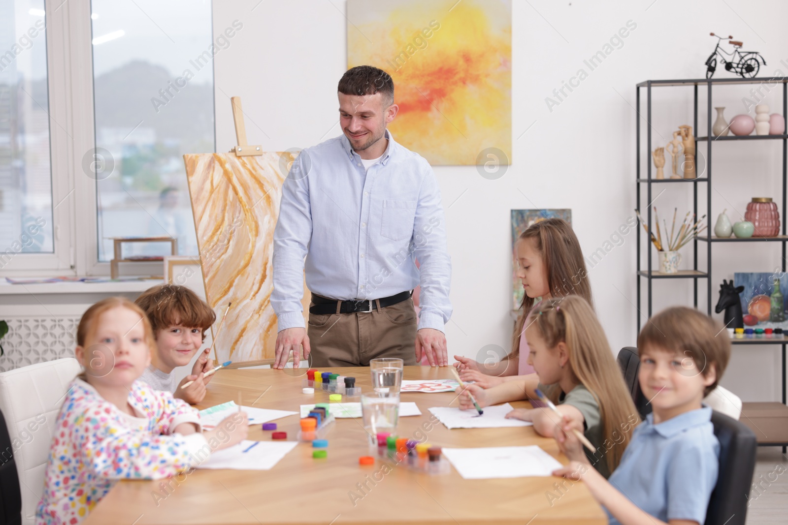 Man teaching kids to draw at painting lesson indoors Photo of Man teaching kids to draw at painting lesson indoors