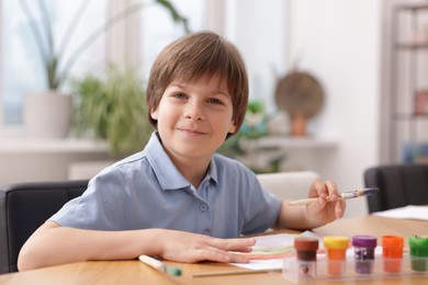 Photo of Cute boy painting at table indoors. Learning to draw