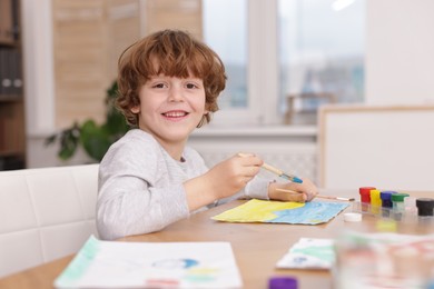 Photo of Cute boy painting at table indoors, space for text. Learning to draw