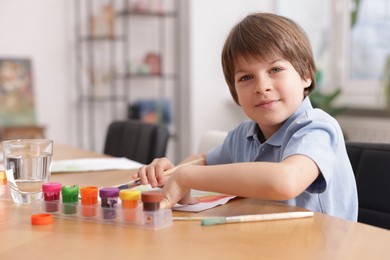 Photo of Cute boy painting at table indoors, space for text. Learning to draw