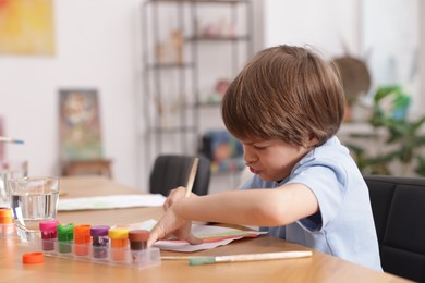 Photo of Cute boy painting at table indoors, space for text. Learning to draw