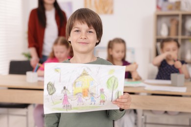Photo of Cute boy showing his drawing during painting lesson indoors, selective focus