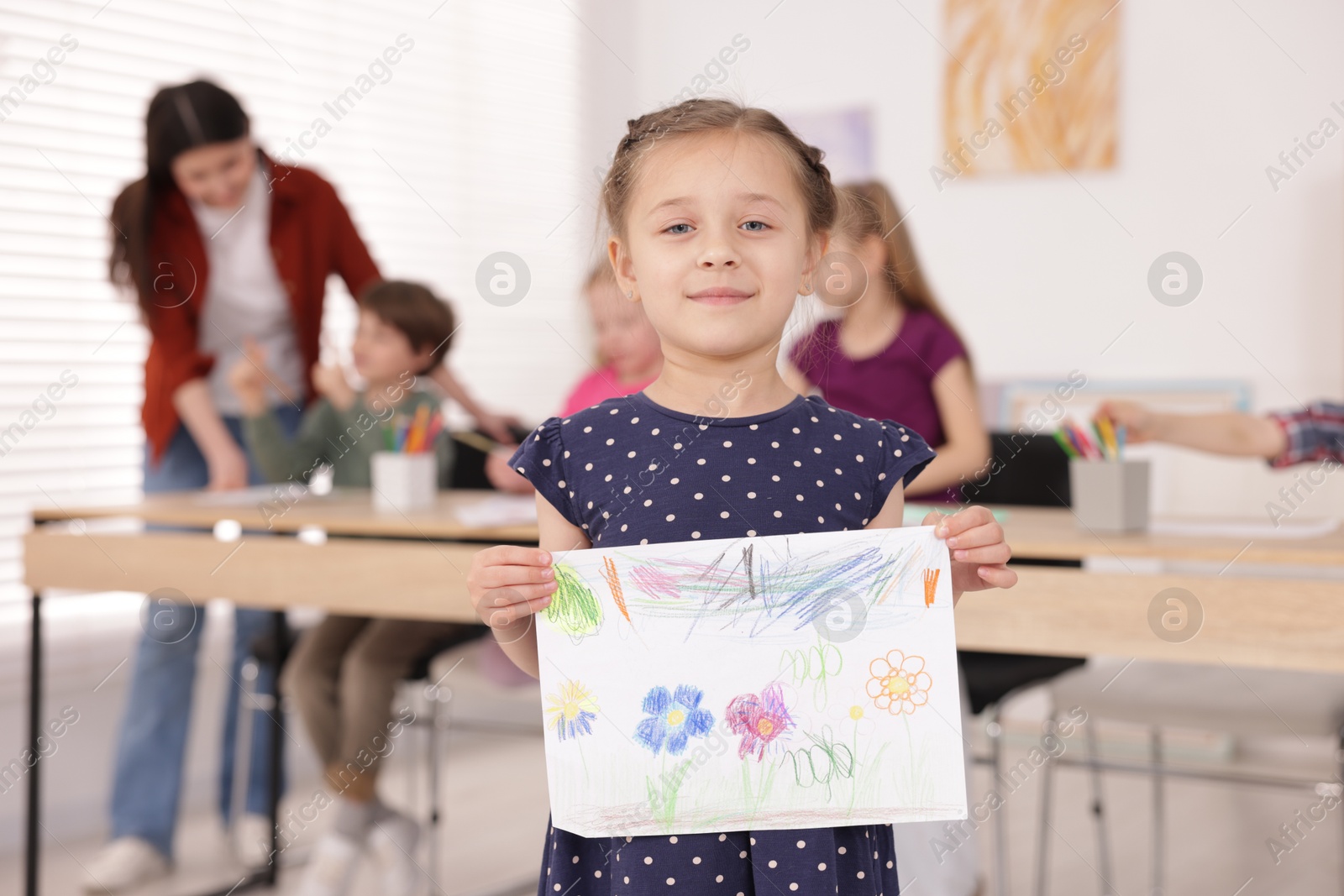 Cute girl showing her drawing during painting lesson indoors, selective focus Photo of Cute girl showing her drawing during painting lesson indoors, selective focus