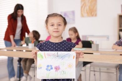 Photo of Cute girl showing her drawing during painting lesson indoors, selective focus