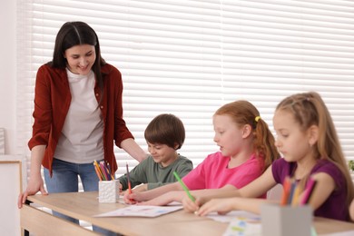 Photo of Woman teaching kids to draw at painting lesson indoors