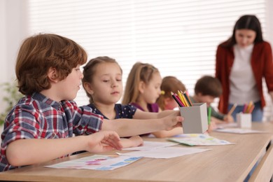 Photo of Woman teaching kids to draw at painting lesson indoors, selective focus