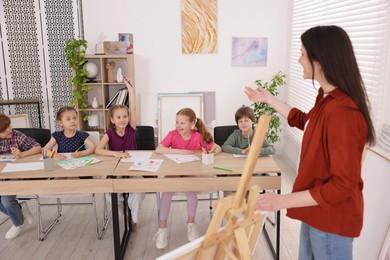 Photo of Woman teaching kids to draw at painting lesson indoors