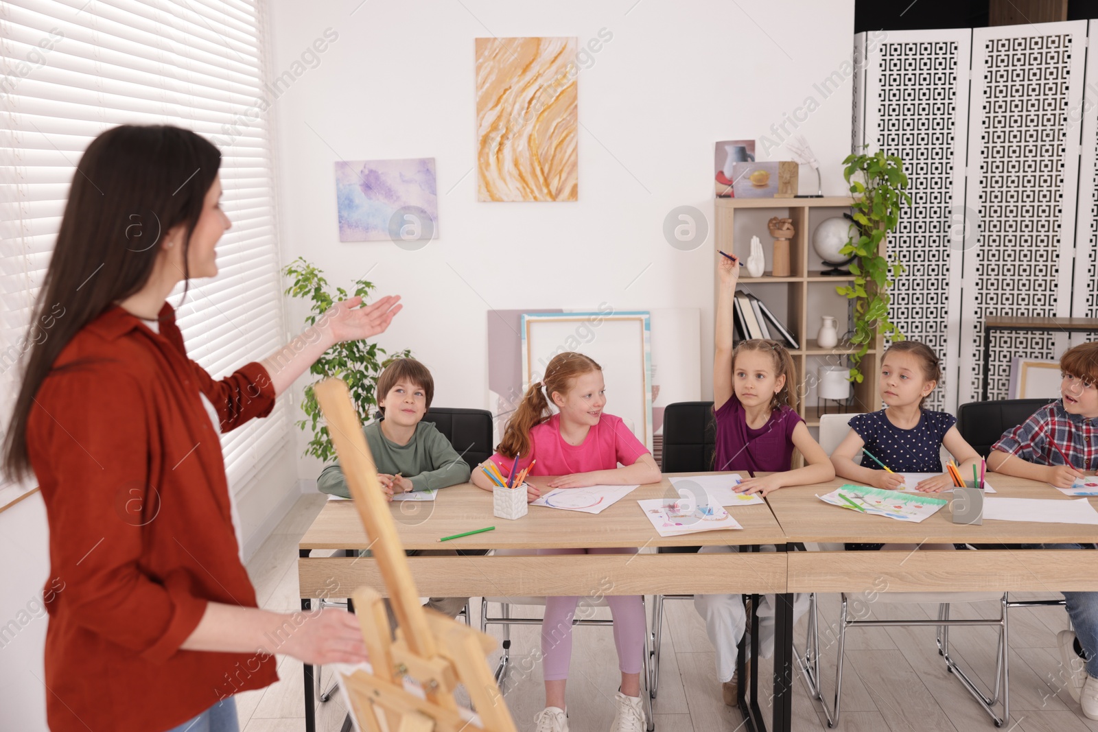 Woman teaching kids to draw at painting lesson indoors Photo of Woman teaching kids to draw at painting lesson indoors