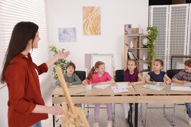 Photo of Woman teaching kids to draw at painting lesson indoors