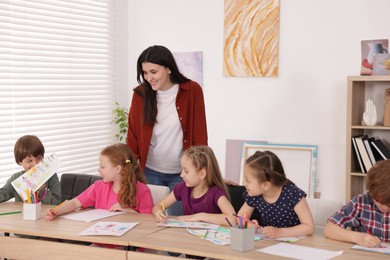 Photo of Woman teaching kids to draw at painting lesson indoors