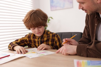 Photo of Man teaching kid to draw at painting lesson indoors, closeup
