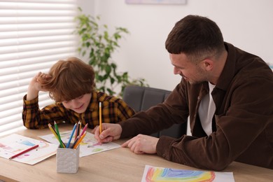 Photo of Man teaching kid to draw at painting lesson indoors
