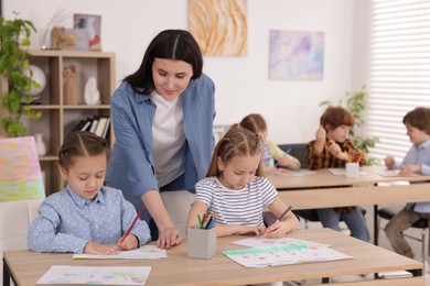 Photo of Woman teaching kids to draw at painting lesson indoors, selective focus