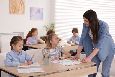 Photo of Woman teaching kids to draw at painting lesson indoors, selective focus