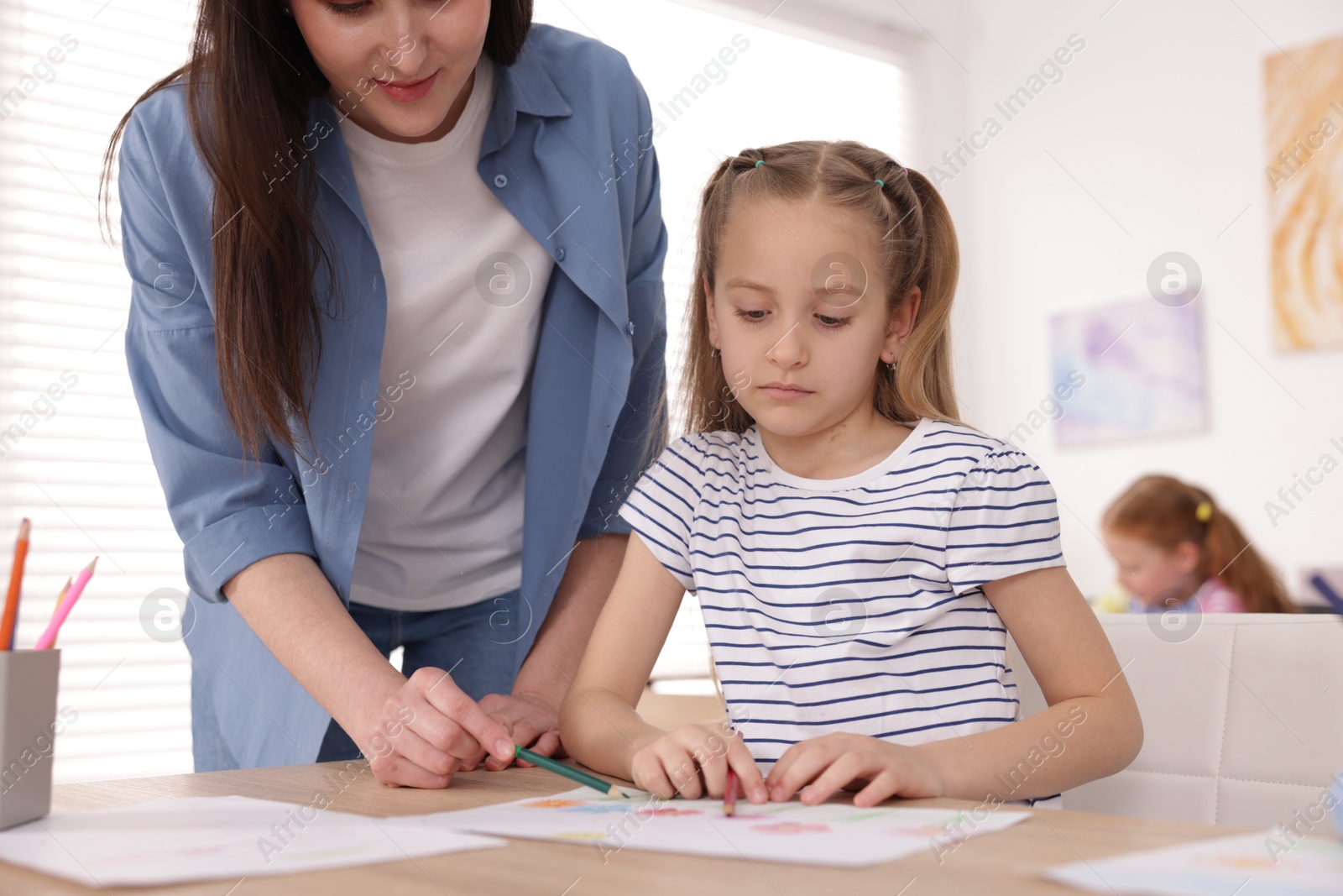 Woman teaching girl to draw at painting lesson indoors, closeup Photo of Woman teaching girl to draw at painting lesson indoors, closeup