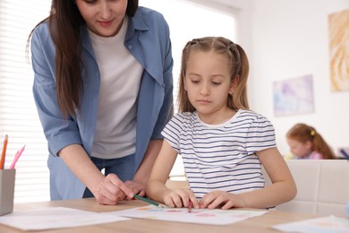 Photo of Woman teaching girl to draw at painting lesson indoors, closeup