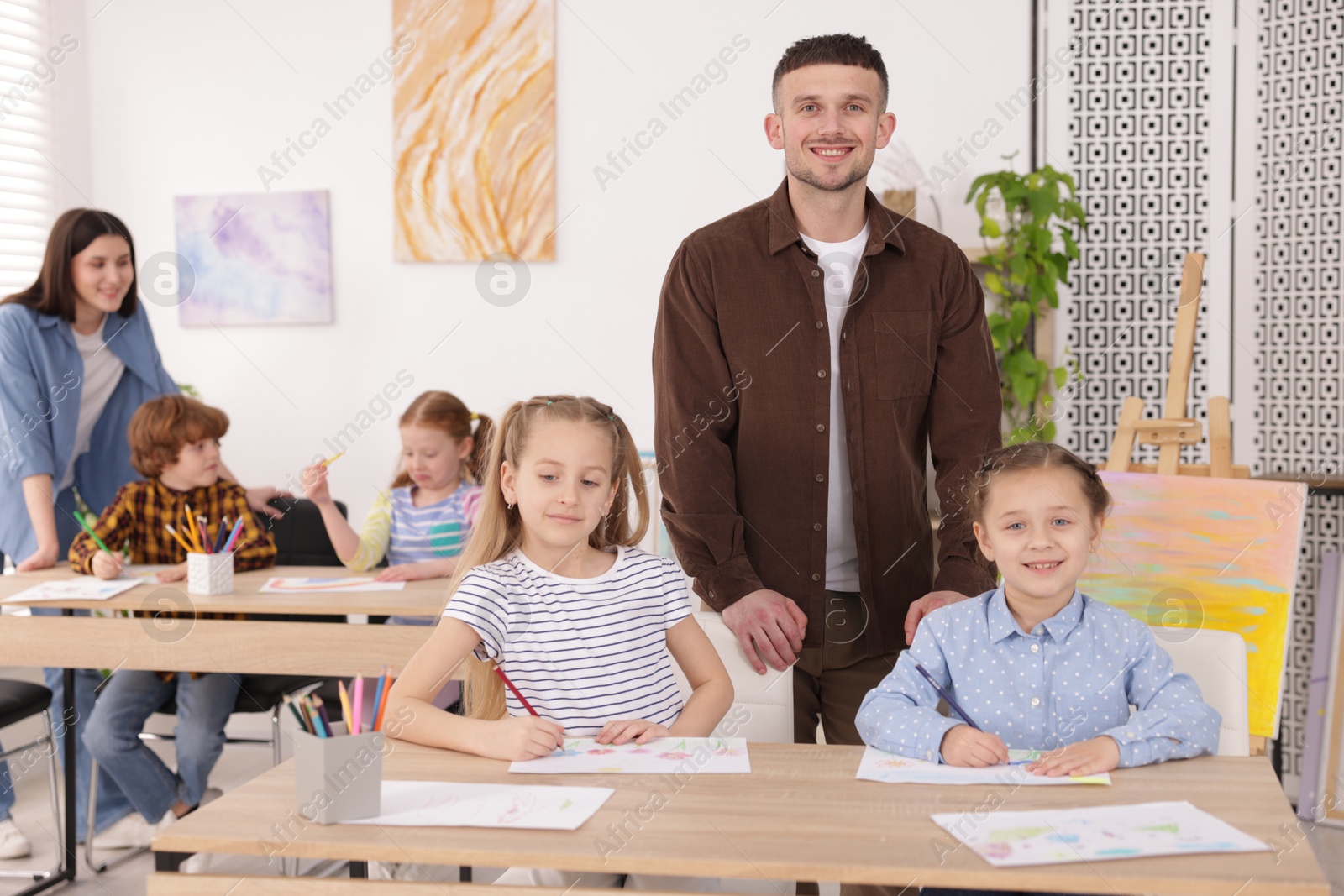 Kids with teachers at painting lesson indoors, selective focus. Learning to draw Photo of Kids with teachers at painting lesson indoors, selective focus. Learning to draw