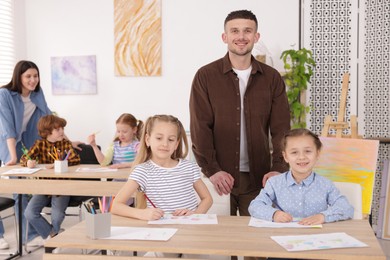 Photo of Kids with teachers at painting lesson indoors, selective focus. Learning to draw