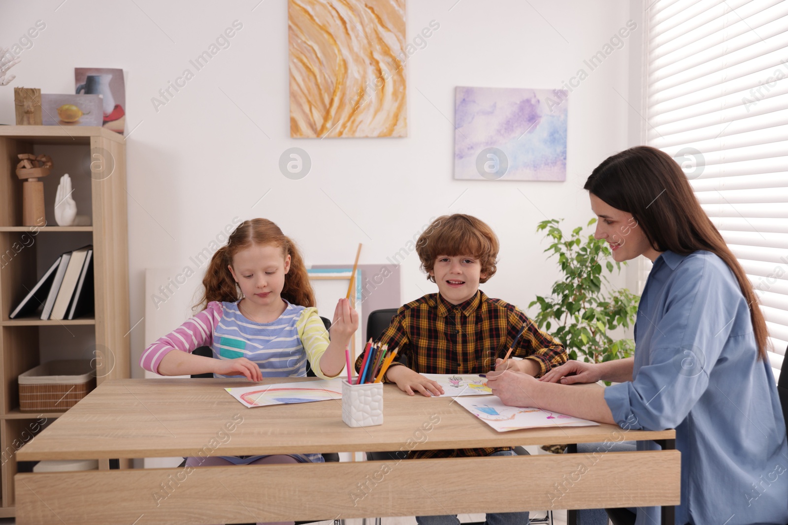 Woman teaching kids to draw at painting lesson indoors Photo of Woman teaching kids to draw at painting lesson indoors
