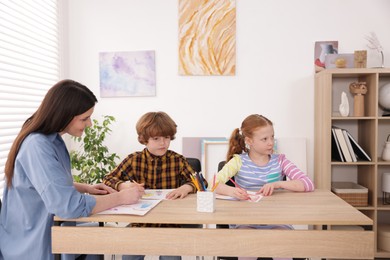 Photo of Woman teaching kids to draw at painting lesson indoors