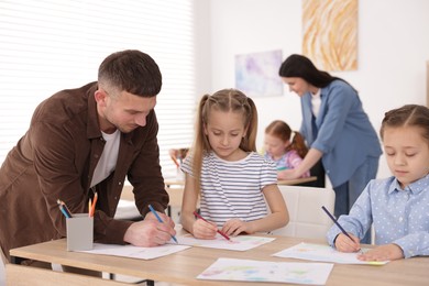 Photo of Kids with teachers at painting lesson indoors, selective focus. Learning to draw
