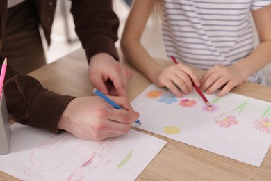 Photo of Man teaching kid to draw at painting lesson indoors, closeup