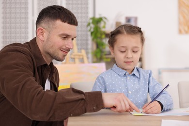 Photo of Man teaching kid to draw at painting lesson indoors