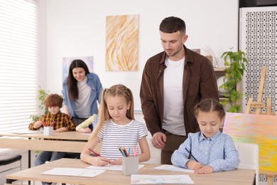 Photo of Kids with teachers at painting lesson indoors, selective focus. Learning to draw