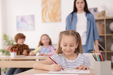 Photo of Kids with teacher at painting lesson indoors, selective focus. Learning to draw