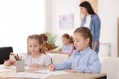 Photo of Kids with teacher at painting lesson indoors, selective focus. Learning to draw