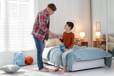 Photo of Father giving his son pocket money at home