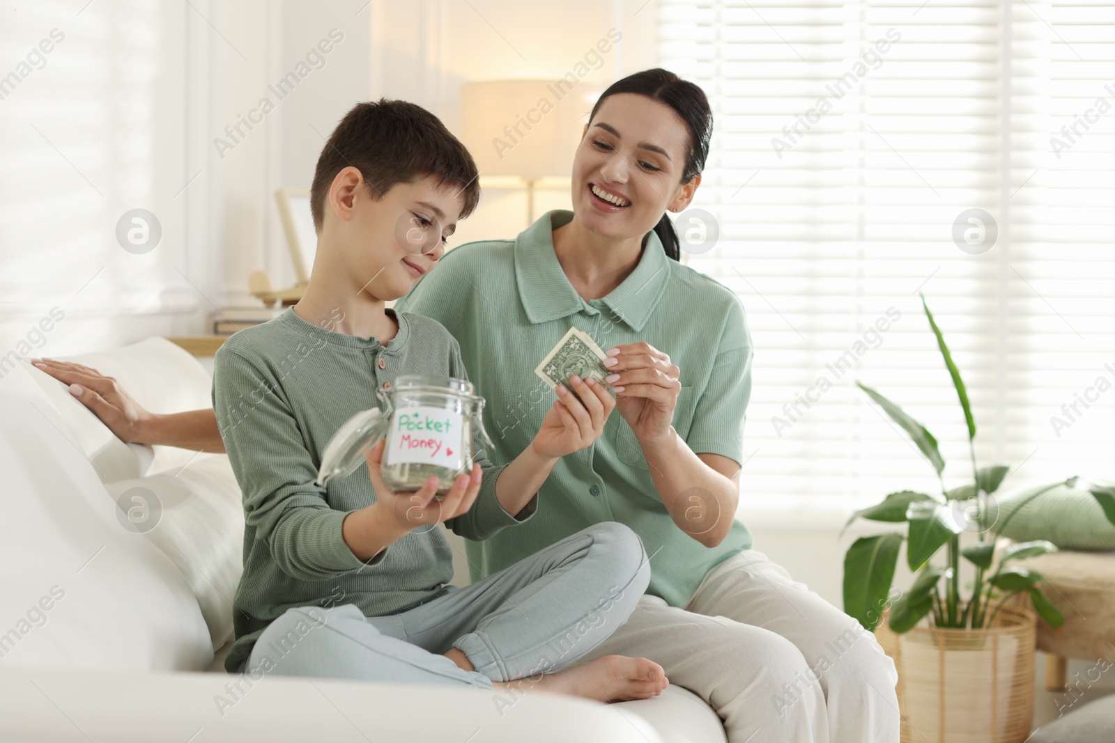 Mom giving her son pocket money on sofa at home Photo of Mom giving her son pocket money on sofa at home