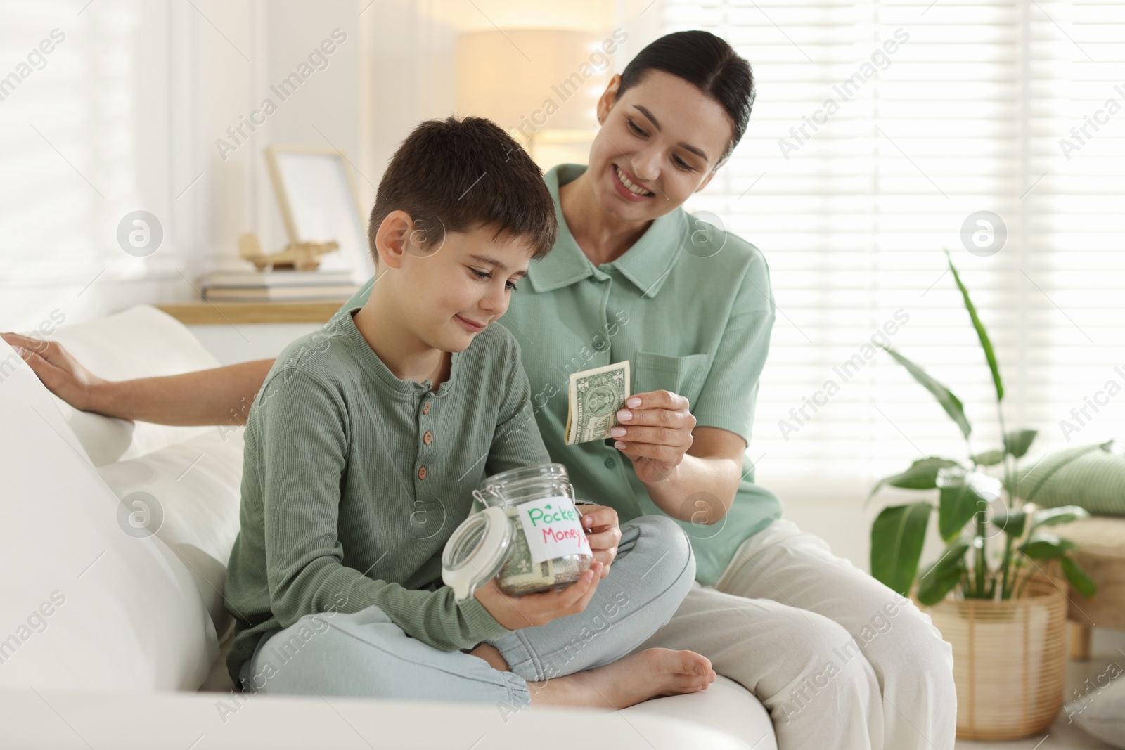 Mom giving her son pocket money on sofa at home Photo of Mom giving her son pocket money on sofa at home