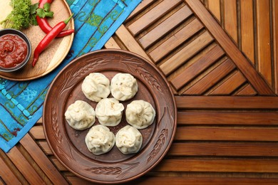 Photo of Delicious khinkali served with sauce on wooden table, flat lay. Space for text