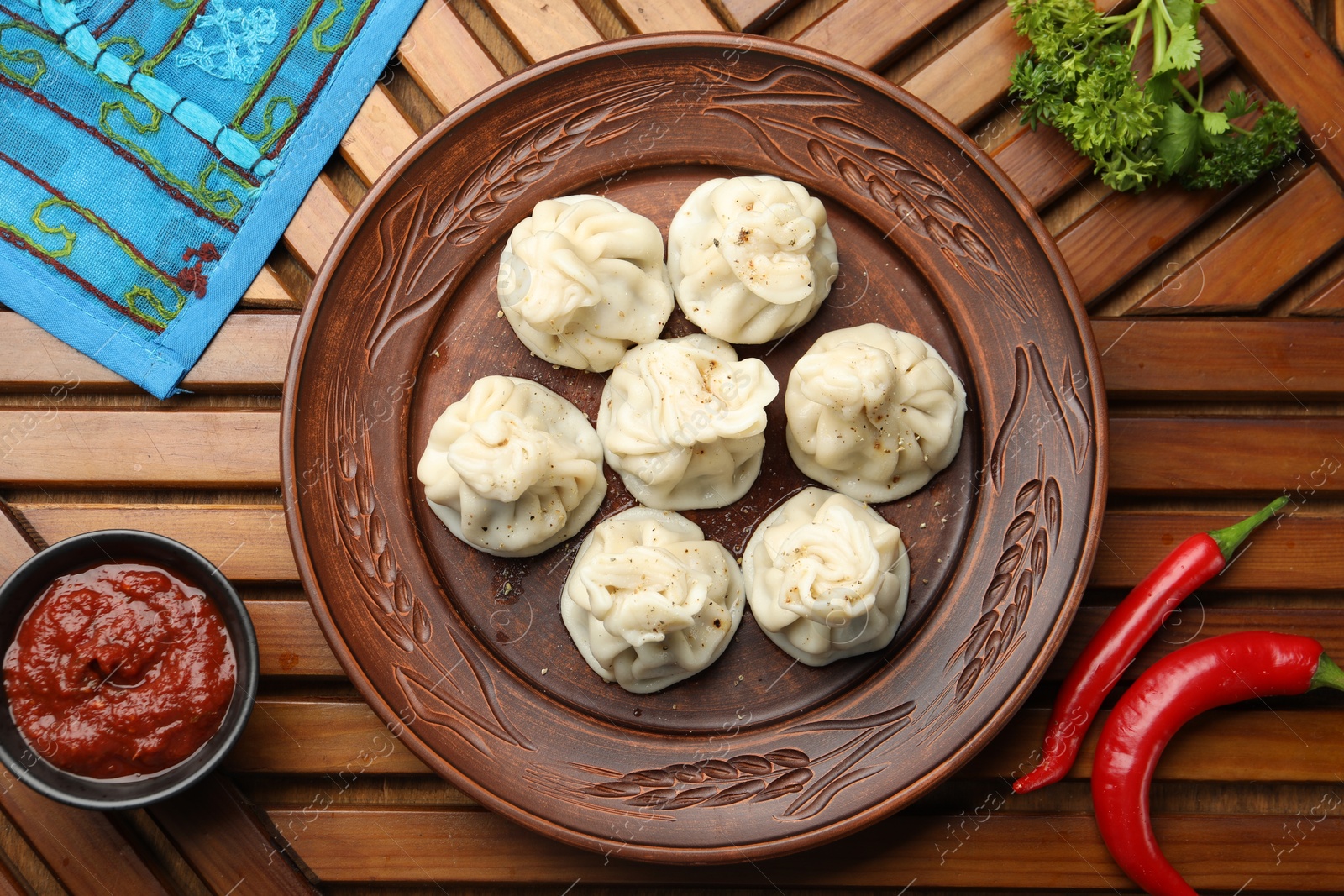 Delicious khinkali served with sauce on wooden table, flat lay Photo of Delicious khinkali served with sauce on wooden table, flat lay