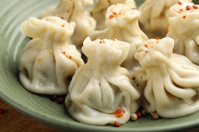Photo of Delicious khinkali with spices in bowl on table, closeup