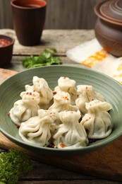 Photo of Delicious khinkali with spices on wooden table, closeup