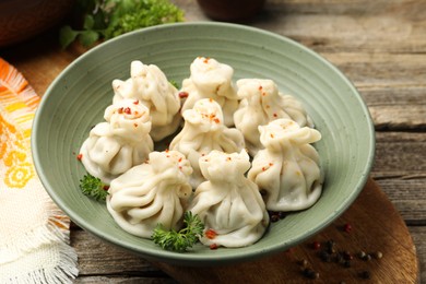 Photo of Delicious khinkali with spices on wooden table, closeup