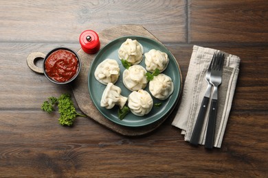 Photo of Delicious khinkali served with cilantro on wooden table, flat lay