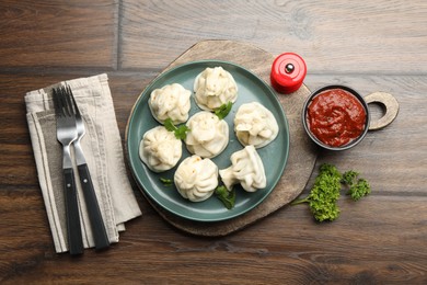 Photo of Delicious khinkali served with cilantro on wooden table, flat lay