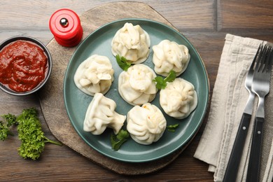 Photo of Delicious khinkali served with cilantro on wooden table, flat lay